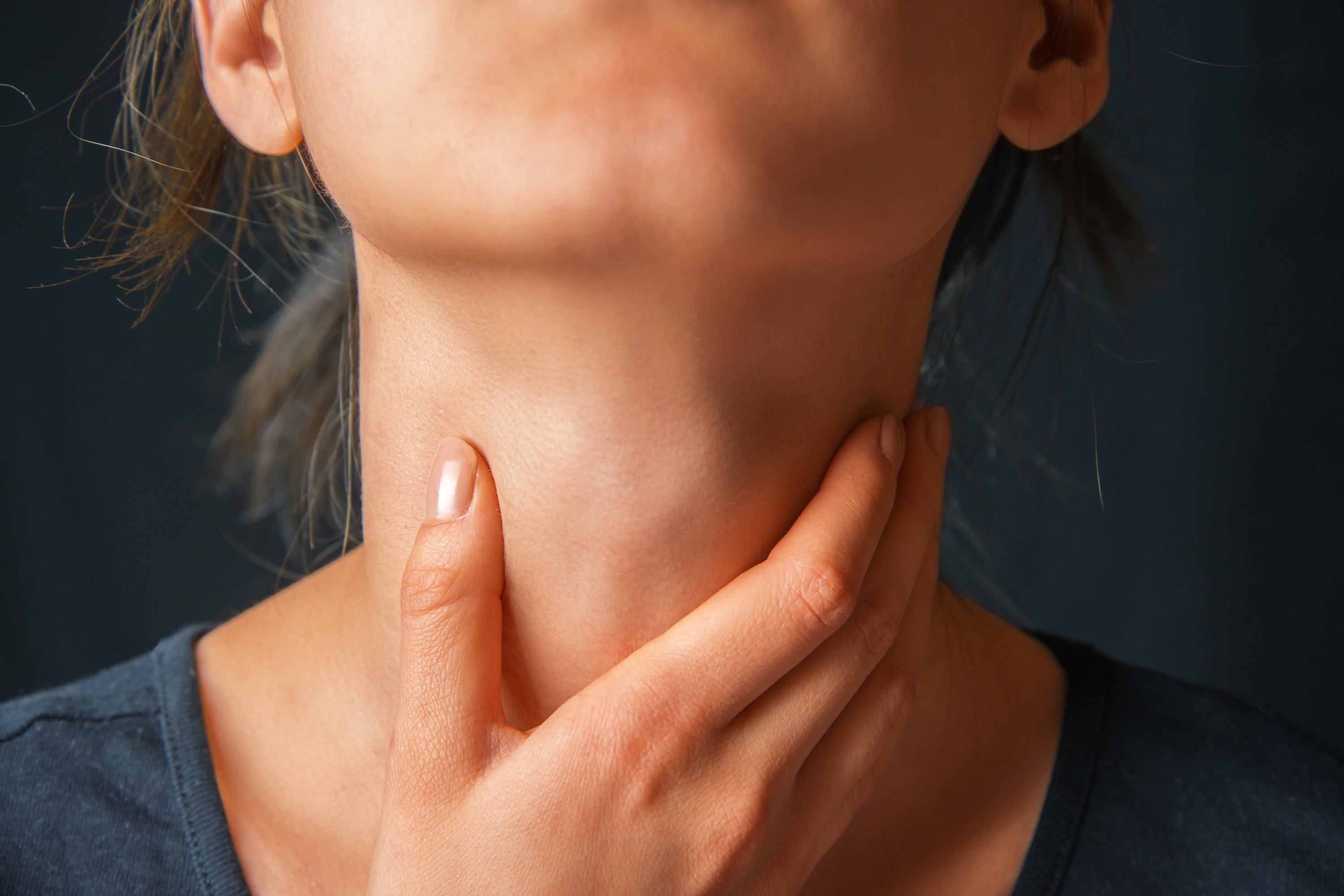 Adobe ENT - Woman holds her throat, sore throat Adobe ENT - Woman holds her throat, sore throat